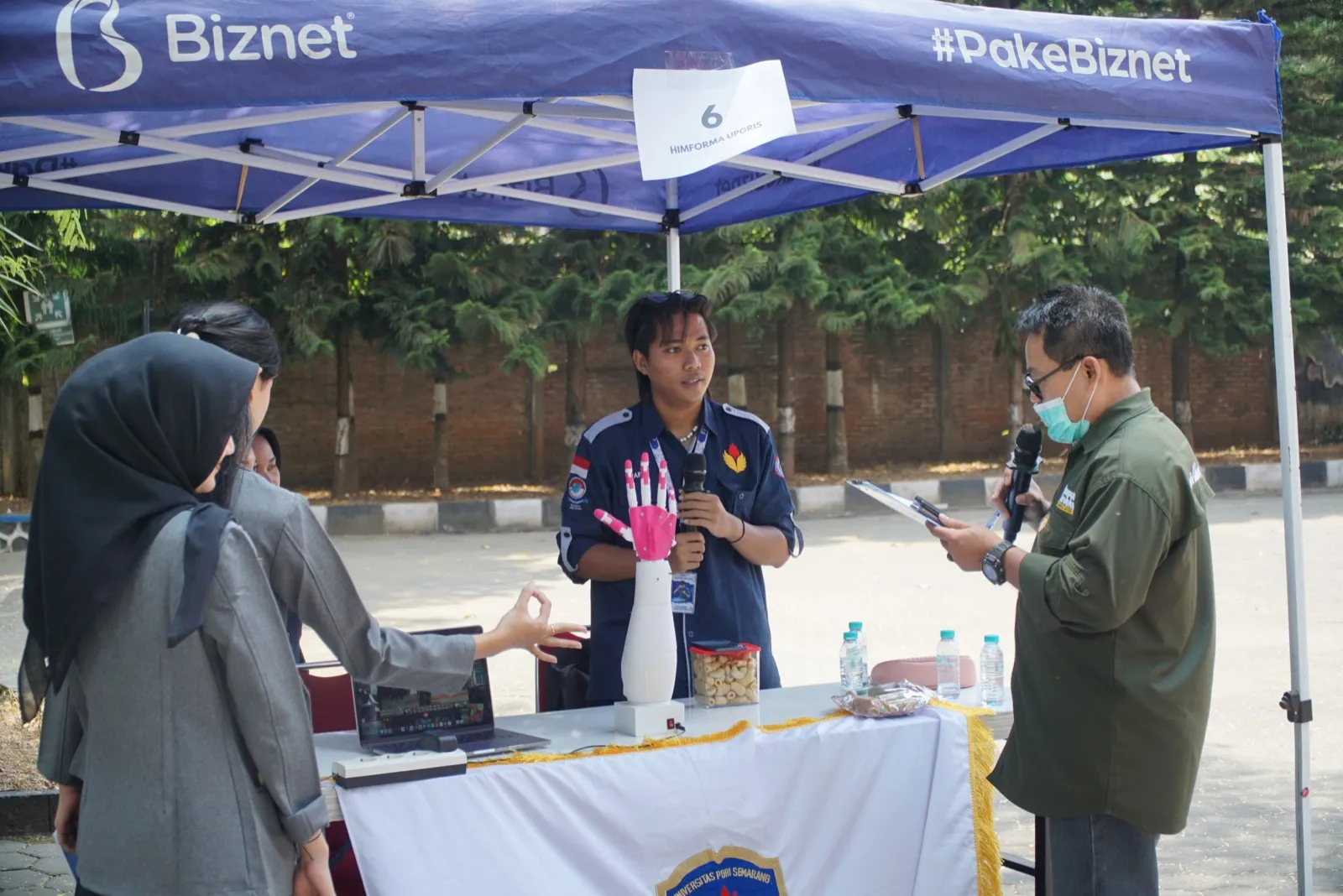 Demoing a robotic hand project to judges at an outdoor campus expo